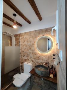 een badkamer met een wastafel, een toilet en een spiegel bij Poseidon Rooms in Kala Nera