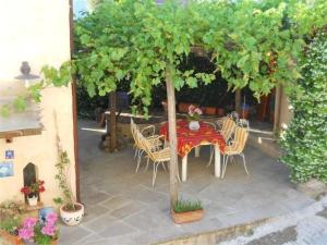 een tafel en stoelen onder een boom op een patio bij Gemütliches Landhaus in ruhiger Lage mit herrlicher Pergola und Blick bis zur Küste in Montigiano