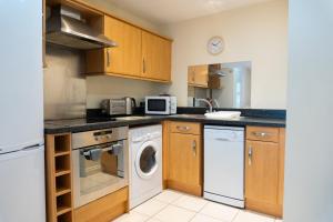 a kitchen with wooden cabinets and a washer and dryer at The Cozy Covert in Spondon, Derby in Derby