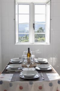une table avec des assiettes et des verres et une fenêtre dans l'établissement Casa A Gateira, à O Casal Pontevedra