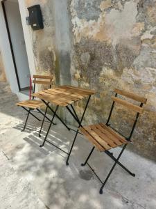 zwei Bänke und ein Tisch und zwei Stühle neben einer Wand in der Unterkunft Karmen's Apartment One in Split
