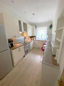 a large kitchen with white cabinets and a window at The Wheelhouse, Gourock in Gourock