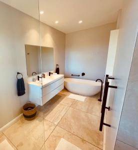 a bathroom with a tub and a sink and a mirror at Rondebos Retreat - Clifftop Peace, Tranquil Bush in Plettenberg Bay