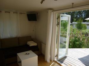 sala de estar con sofá y puerta corredera de cristal en Kleines Ferienhaus - Tiny house - auf Gotland 700 Meter zum Meer en Ljugarn
