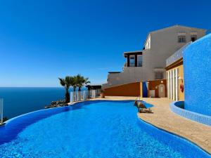 una piscina frente a una casa con el océano en Apartamento Panorama X0025, en Benitachell