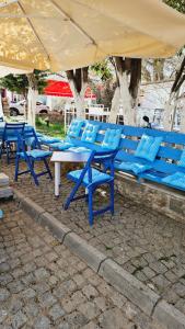 a group of blue tables and chairs under an umbrella at Ada Kalimera Bozcaada in Bozcaada