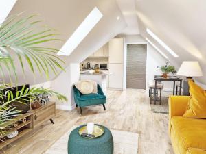a living room with a yellow couch and a green chair at Roseland Penthouse - Arundel in Arundel