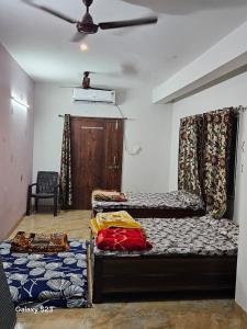 a room with three beds and a ceiling fan at Kshipra Home Stays in Ujjain