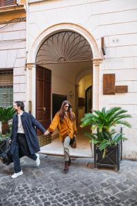 Ein Mann und eine Frau halten vor einem Gebäude Händchen. in der Unterkunft Parisii Bocca di Leone 88 in Rom + 40 Fotos