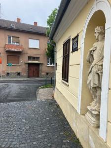 uma estátua de um homem ao lado de um edifício em Mohás Vendégház Kőszeg em Kőszeg