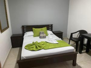 Un dormitorio con una cama con una manta verde. en Hotel El Deportista, en Medellín