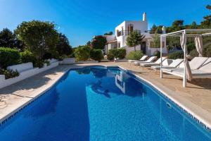 una piscina de agua azul frente a una casa en Casa Aalaya: Ibiza Mediterranean Retreat, en Illes Balears