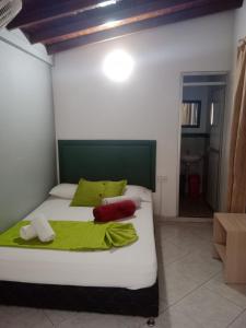 Schlafzimmer mit einem Bett mit grünen und roten Kissen in der Unterkunft Hotel El Deportista in Medellín