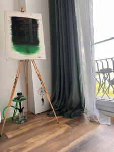 a painting on a tripod next to a window at Cozy and Luminous Loft Apartment! in Ştefăneştii de Jos
