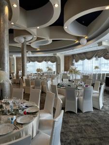 un salón de banquetes con mesas blancas y sillas blancas en Black Tulip Hotel, en Dej