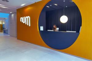 a woman is sitting at a reception desk in a lobby at Num Hotel in Salou