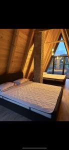uma cama num sótão com uma grande janela em Vikendica Peric Zelinje 