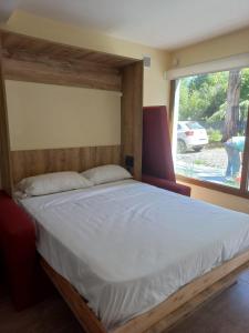 a bed with a wooden headboard in a room with a window at Cabañas Duendes y Hadas in El Bolsón
