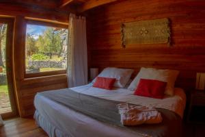 Cama en habitación de madera con ventana en Rocanegra Mountain Lodge, en Las Trancas