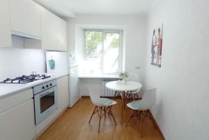a white kitchen with a table and chairs in it at 1 кімнатні просторі апартаменти біля Сіті- центру 2 поверх 9 поверхового будинку in Mykolaiv