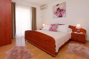 Sunshine Apartment Doda في فيلا لوكا: غرفة نوم بسرير خشبي كبير مع سجادتين