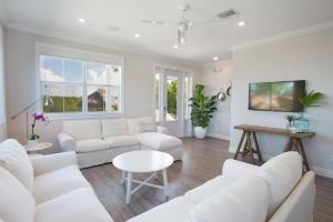 a white living room with white couches and a table at Isla Mirabelle - Waterfront Boutique Resort, Htd Pool, Dock, Walkable in Islamorada