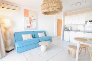 a living room with a blue couch and a kitchen at Apartamentos Sunset Oasis Ibiza - Only Adults in San Antonio Bay