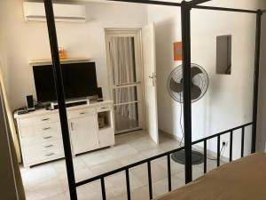 a room with a television and a dresser with a fan at La Maison Jaune in Poponguine