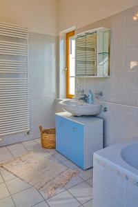 a bathroom with a sink and a mirror and a tub at Ferienhaus am Mühlbach Ammersee in Utting am Ammersee