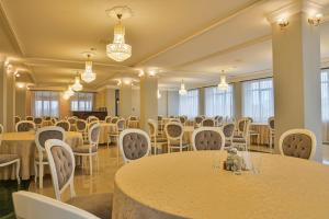 un salón de banquetes con mesas, sillas y lámparas de araña en Hotel Abi - Baile Felix, en Băile Felix