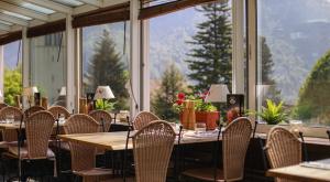 um restaurante com mesas e cadeiras e uma grande janela em Le Saint Georges em Gruyères