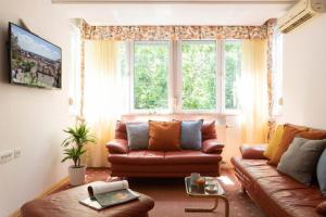 ein Wohnzimmer mit einem braunen Ledersofa und einem Fenster in der Unterkunft Kennedy Apartment URBAN STAY in Zagreb