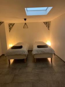 two twin beds in a room with a skylight at Le Mirabeau in Hénin-Beaumont