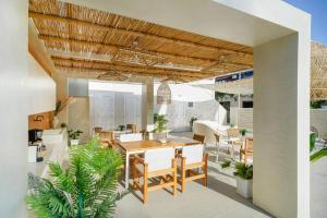 an outdoor patio with a wooden table and chairs at Ester Luxury Rooms in Skala Potamias
