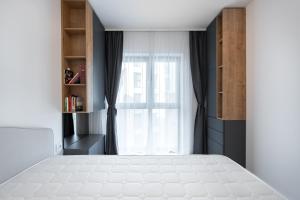 ein Schlafzimmer mit einem weißen Bett und einem Fenster in der Unterkunft Golden Grove I 1 BR apartment near Romexpo in Bukarest