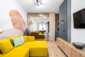 ein Wohnzimmer mit einem gelben Sofa und einem TV in der Unterkunft Golden Grove I 1 BR apartment near Romexpo in Bukarest