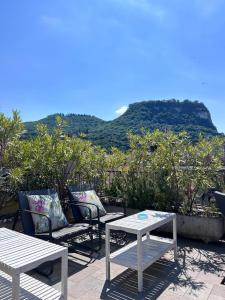 dos mesas blancas y sillas con una montaña en el fondo en Casa Cavour, en Garda