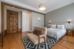a bedroom with a bed and a chair and a television at GuestReady - Cedofeita Pool Suite 3 in Porto