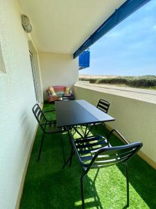 d'un balcon avec une table, des chaises et un canapé. dans l'établissement Charmant appartement en front de mer avec piscine, à Lacanau-Océan
