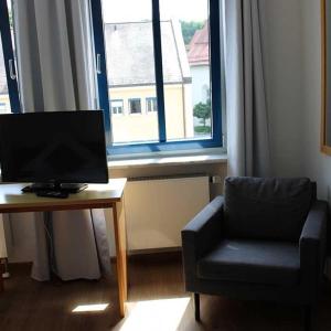 德根多夫的住宿－Stadthotel Deggendorf，客厅配有椅子和桌子上的电脑
