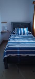 a bed with a blue and white striped comforter at La Casita II in Cochabamba