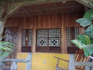 drewniany budynek z oknami i krzesłem z przodu w obiekcie Goldsky Seaview Resort Lagang Green Room w mieście San Juan