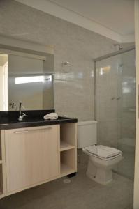 uma casa de banho com um WC e uma cabina de duche em vidro. em Oásis do Sol em Porto de Galinhas