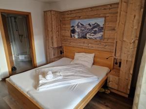 łóżko w pokoju z drewnianą ścianą w obiekcie Adler Kaprun, Golf 'n' Ski and Mountain Biking. w Kaprunie