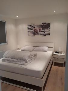 1 dormitorio con 1 cama blanca grande con sábanas blancas en Ferienchalet an der Grenze zwischen Brabant und Zeeland, en De Heen