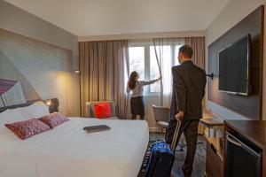 a man and woman looking out of a window in a hotel room at Novotel Sao Jose dos Campos in São José dos Campos