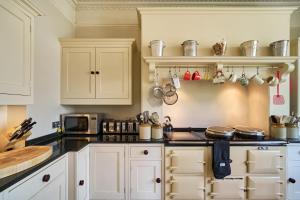 a kitchen with white cabinets and a black counter top at Berkeley House near Bath in Bath