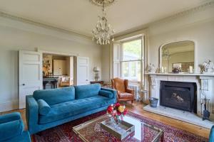 a living room with a blue couch and a fireplace at Berkeley House near Bath in Bath