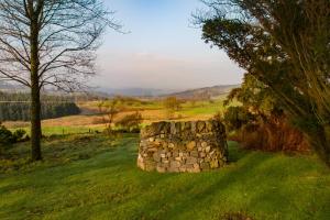 a stone wall in the middle of a field at Covenanters Cottage , Balmaclellan in Castle Douglas