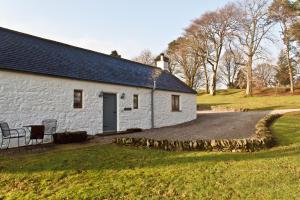 a white building with a table and chairs in front of it at Covenanters Cottage , Balmaclellan in Castle Douglas